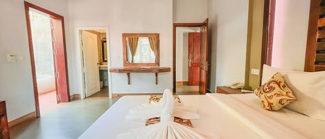 A hotel room with a bed, a bedside table with a phone, a mirror, and a bathroom visible through an open door.