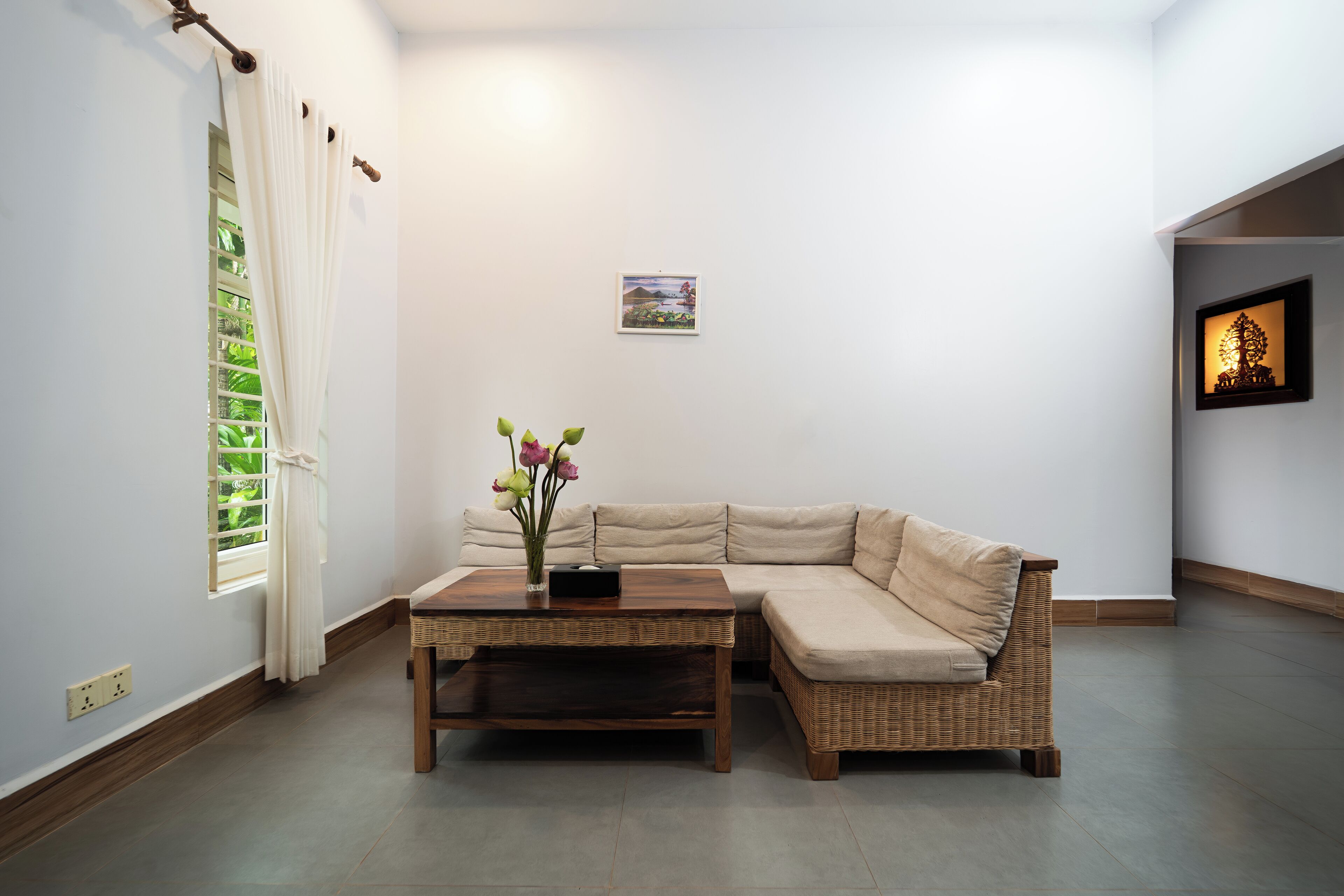 A living room with a beige sofa, a wooden coffee table, and a small vase with flowers.