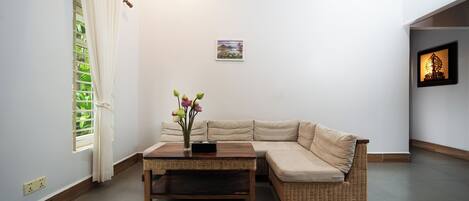 A living room with a beige sofa, a wooden coffee table, and a small vase with flowers.