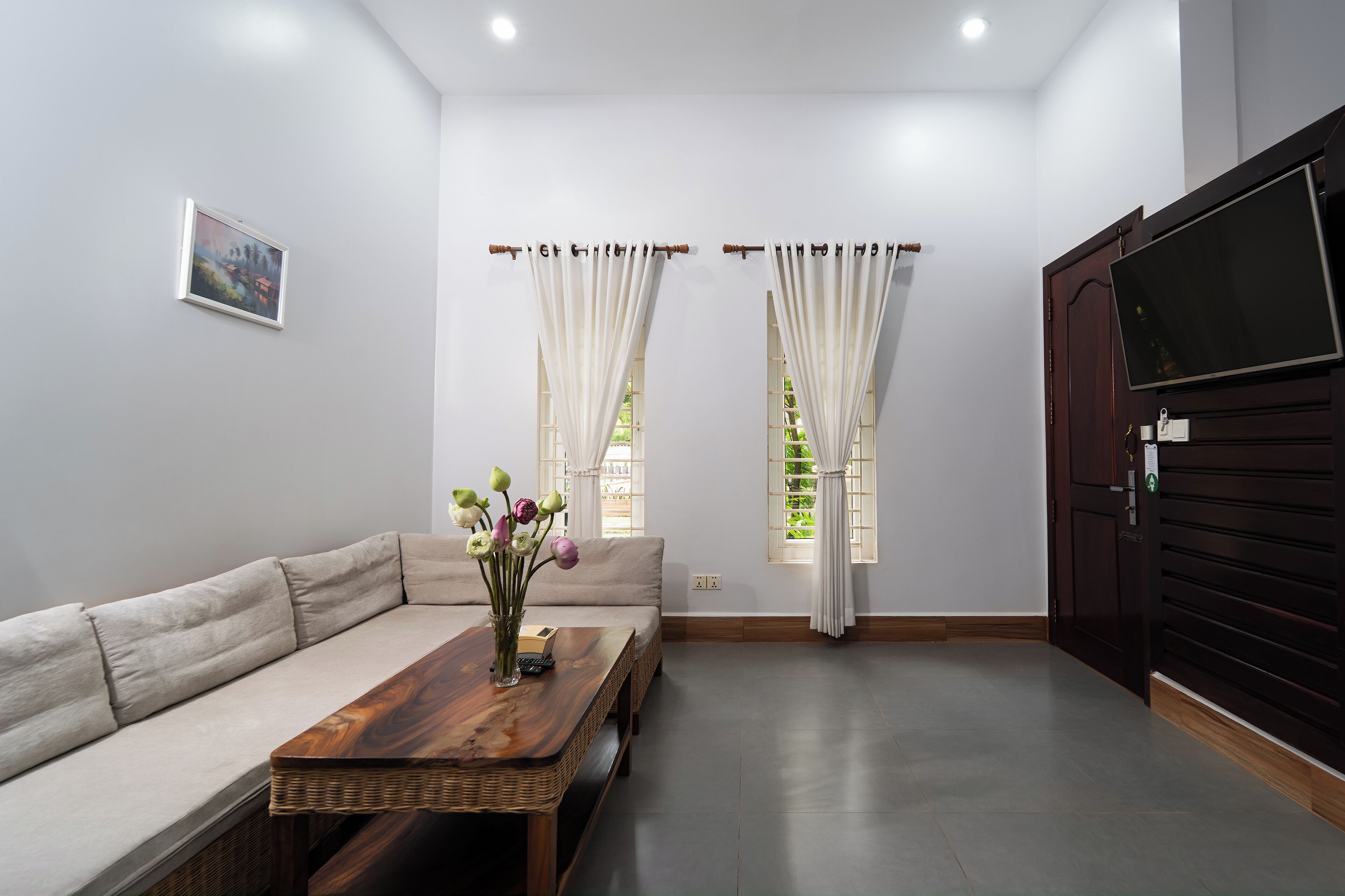 A modern living room with a sofa, a wooden coffee table, and a TV mounted on the wall.