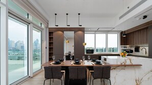 A modern kitchen with a marble island, large windows, and a city view. - Maison Privee - Deluxe 3BR Apt w/ Dubai Marina View and Beach Access (Dubai)