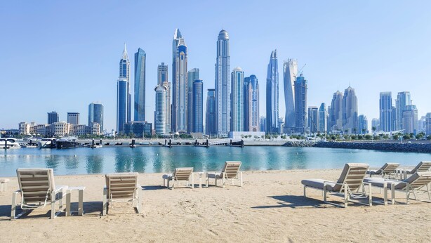 A beach with lounge chairs and a marina with boats. - Maison Privee - Deluxe 3BR Apt w/ Dubai Marina View and Beach Access (Dubai)