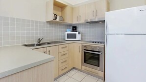 Een kleine keuken met een magnetron, oven en koelkast.