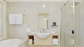 Een moderne badkamer met een bad, een wastafel, een spiegel en een douchecabine van glas.
