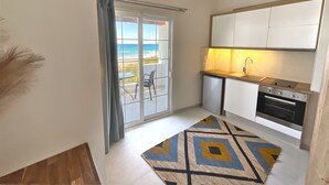 Una cuina compacta amb vista a l'oceà, una zona de menjador reduïda i una catifes amb motius.