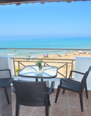 Un balcon avec une table et des chaises donnant sur une plage.