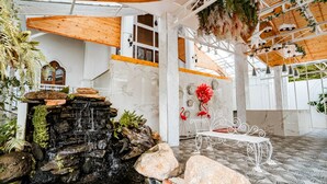 Un espacio interior moderno con una cascada, paredes de mármol blanco y detalles de madera.
