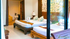 Habitación de hotel con dos camas, un banco de madera, un lavamanos y una pared decorativa.