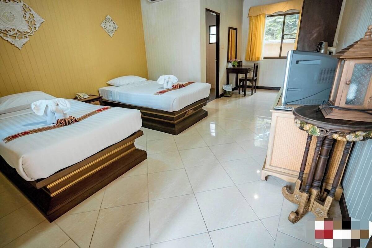 Habitación de hotel con dos camas, televisor, una mesita y un armario.