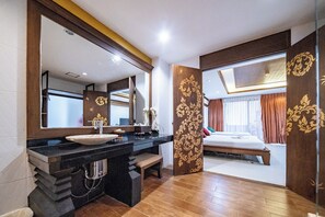 A modern bathroom with a large mirror, a black countertop, and a wooden floor.