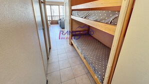 A narrow hallway with a wooden bunk bed, a door leading to a balcony, and a tiled floor. - Studio Cabin in center Valloire with Free Wifi (VALLOIRE)