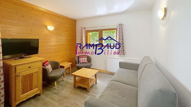 Una sala de estar acogedora con una pared de madera, un televisor de pantalla plana, un sofá, una mesa de centro y un mueble pequeño.