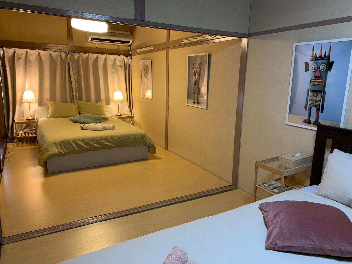 A hotel room with a bed, bedside tables, a nightstand, a lamp, and a wall-mounted artwork.
