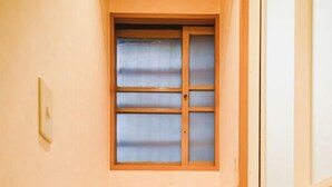 A narrow hallway with a wooden-framed window and a white shelf unit against the wall. - North Shinjuku house (Tokyo)