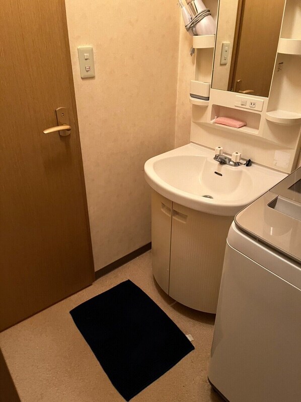 A compact bathroom with a white sink, a mirror, and a towel rack.