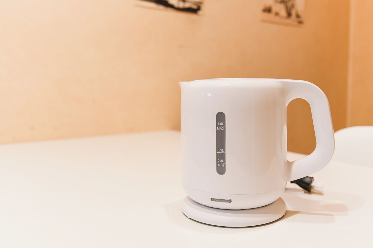 A white electric kettle with measurement markings on its side.