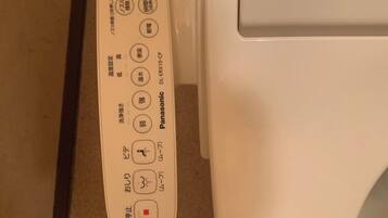 A toilet with a control panel featuring buttons for functions like flush, bidet, and seat heating.