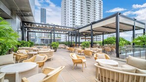 A rooftop terrace with outdoor seating and a view of surrounding buildings.