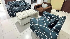A living room with two sofas, a coffee table, and a brown armchair. - Ambon Residence Syariah (Ambon)