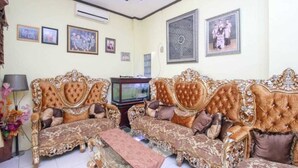 A living room with ornate sofas, a television, and framed pictures on the walls. - Ambon Residence Syariah (Ambon)