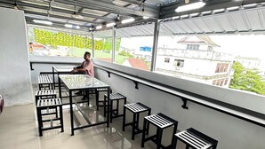 A modern indoor space with a high ceiling, metal beams, and a balcony with black metal chairs and tables. - Ambon Residence Syariah (Ambon)