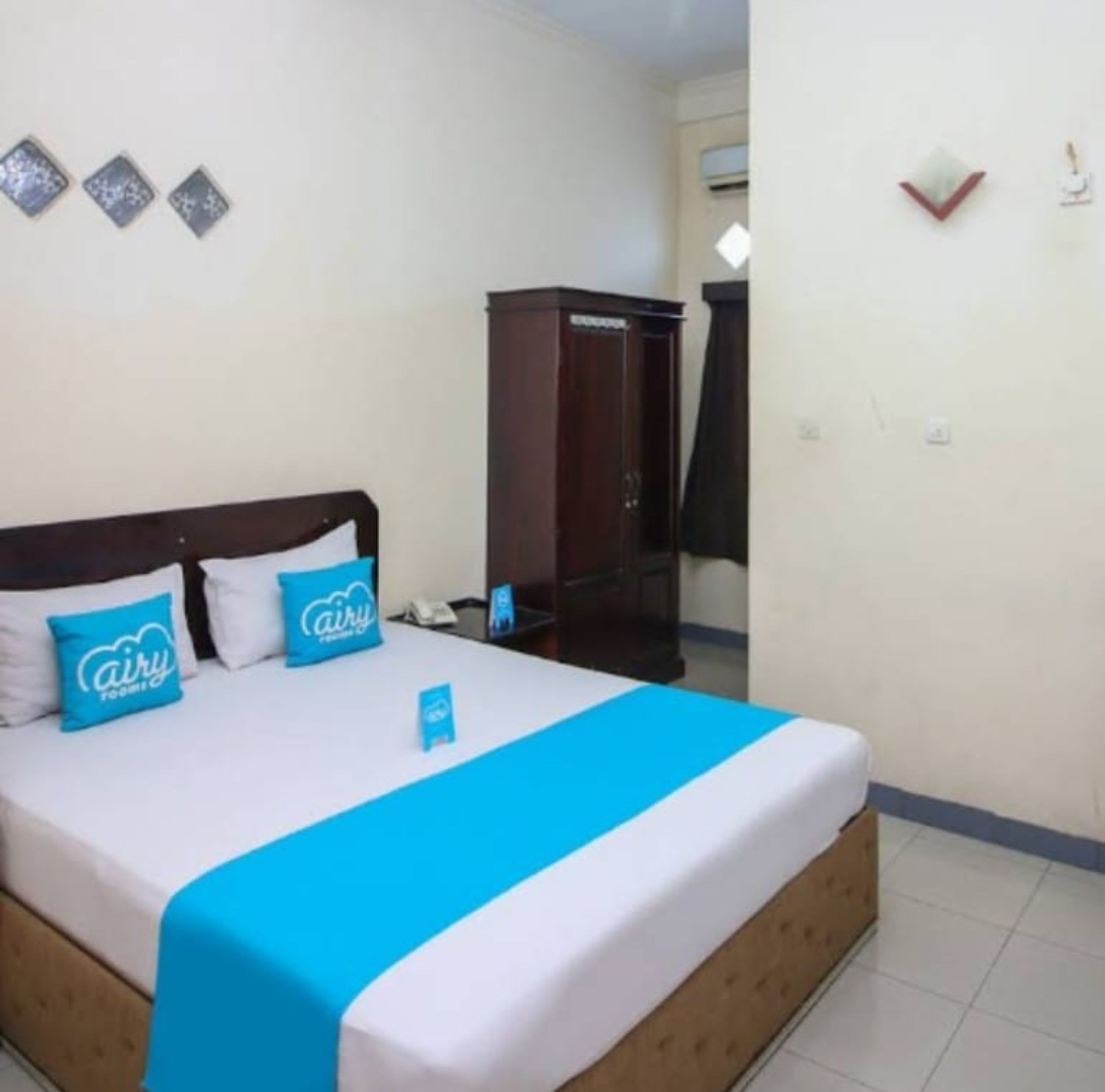 A hotel room with a bed, a wardrobe, and a desk.
