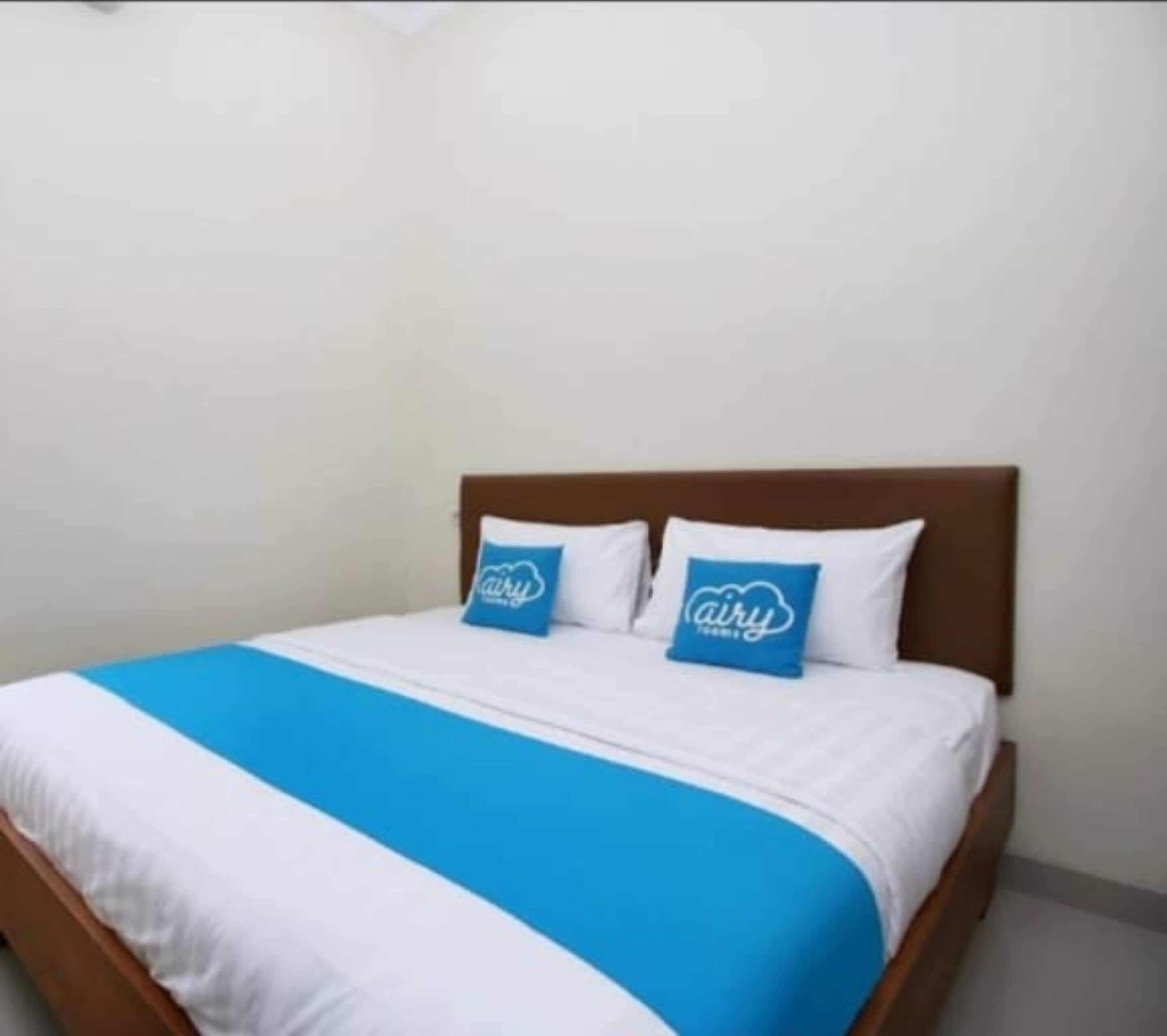 A neatly made bed with a blue and white bedspread and two matching pillows.