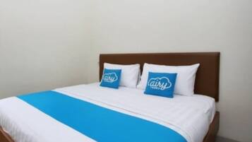 A neatly made bed with a blue and white bedspread and two matching pillows.