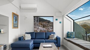 A modern living room with a blue sofa, a coffee table, and a large window with a cityscape view.