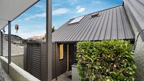 A residential building with a metal roof, a small attached garage, and a green hedge.