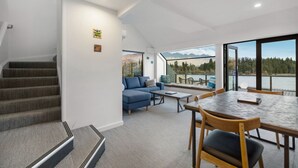 A modern interior with a staircase, a living area with a sofa and coffee table, and a dining area with a table and chairs.