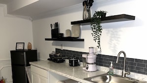 Une cuisine équipée d’un évier, d’un plan de travail, d’appareils électroménagers noirs et d’une plante suspendue.