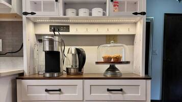 A kitchen with a coffee machine, a tea kettle, and a display case with baked goods.