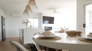 Una cocina moderna con comedor, que incluye una mesa redonda con sillas, un televisor y un ventilador de techo.
