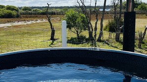 Una piscina exterior cristalina con vistas a un campo cubierto de hierba y árboles.
