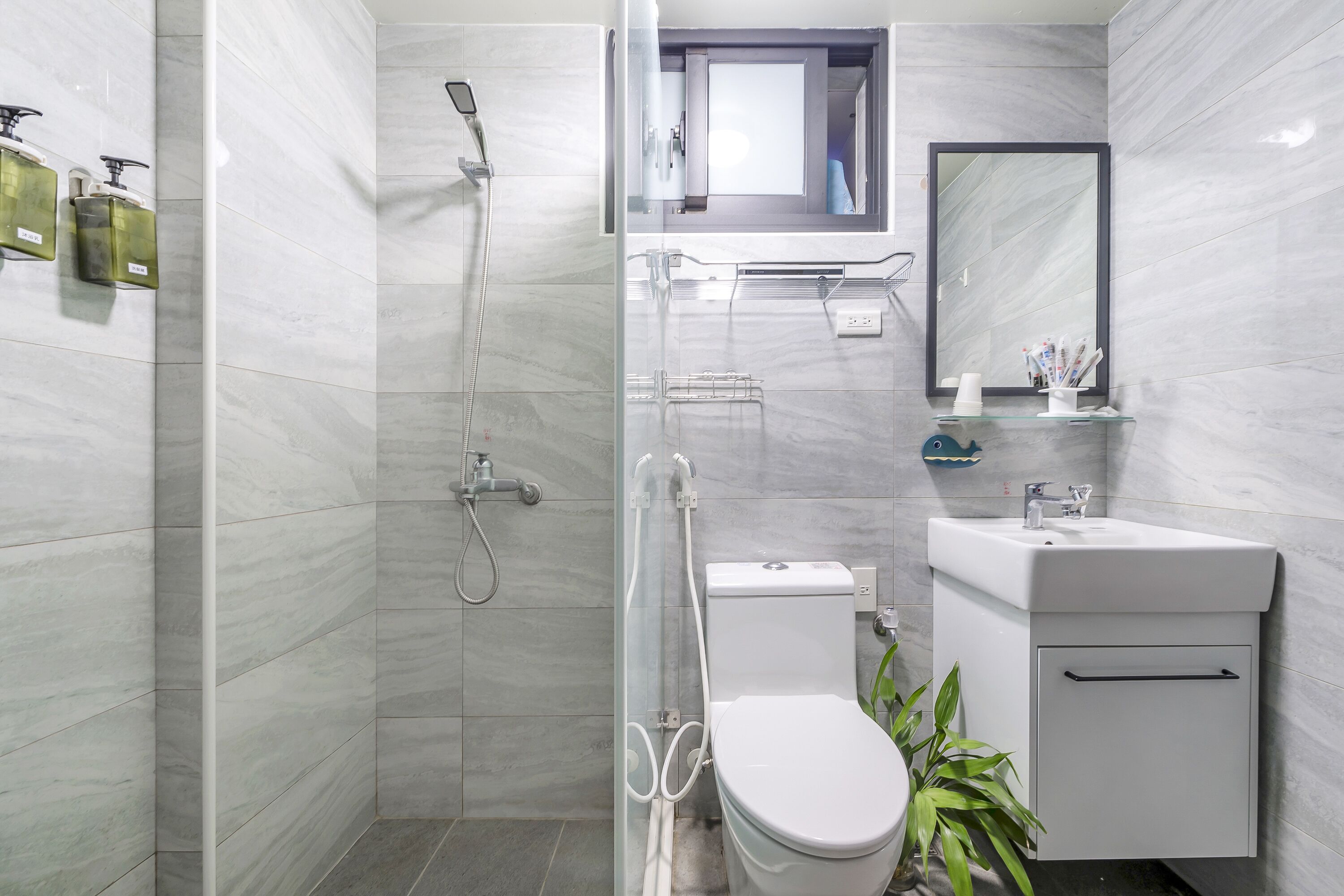 A modern bathroom with a shower, toilet, sink, and mirror.