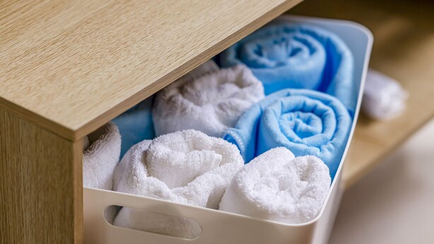A storage box with neatly folded white and blue towels.