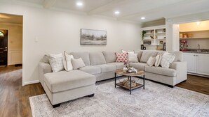A living room with a beige sectional sofa, a coffee table, and a patterned rug. - Roomy Houston Rental w/ Home Office & Private Pool (Houston)