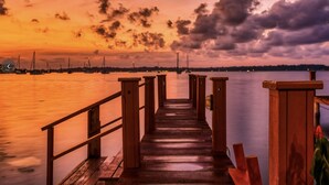 A wooden pier extending into calm water with a sunset in the background. - Los balcones over the sea (Bocas del Toro)