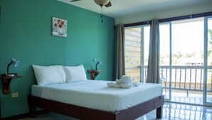 A bedroom with a bed, two bedside tables with lamps, a ceiling fan, a window with curtains, and a view of the outdoors. - Los balcones over the sea (Bocas del Toro)