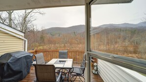 A covered deck with a table and chairs, overlooking a mountainous landscape. - Mtn-View Condo w/ Lookout Deck in Banner Elk! (Banner Elk)