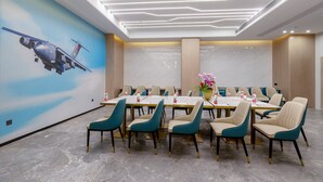 A conference room with a long table, teal chairs, and a mural of a helicopter on the wall. - Grand Yuntian Yue Hotel Shenzhen Shekou  (Shenzhen)