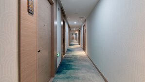 A long, narrow hallway with wooden doors on one side and a patterned wall on the other. - Grand Yuntian Yue Hotel Shenzhen Shekou  (Shenzhen)