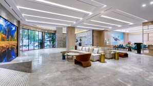 A spacious lobby with a modern design, featuring a reception area, seating arrangements, and a large mural on the wall. - Grand Yuntian Yue Hotel Shenzhen Shekou  (Shenzhen)