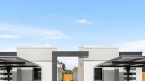 A modern building with a symmetrical facade, featuring a central entrance and two covered areas on either side.