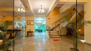 A spacious lobby with a marble floor, a staircase, and potted plants. - Gharial Bagh Resort (Sawai Madhopur)