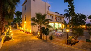 A modern hotel with a well-lit entrance, outdoor seating area, and a staircase leading to the entrance. - Gharial Bagh Resort (Sawai Madhopur)