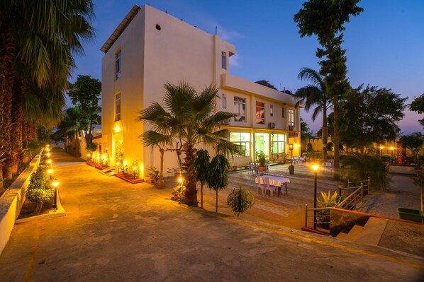Un hotel moderno con una entrada bien iluminada, un área de estar al aire libre y una escalera que conduce a la entrada.