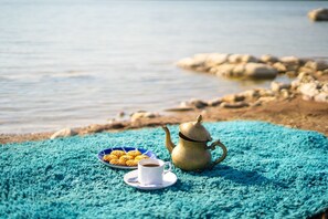 Una mesa con un calentador de agua, una taza de café y un plato de galletas junto al agua.