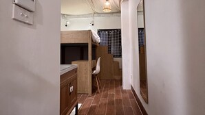 A narrow hallway with a bunk bed, wooden furniture, and a tiled floor.